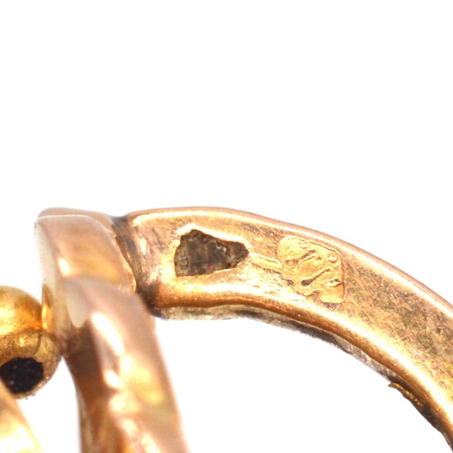Close-up of 19th-century 18ct gold mini hoop earrings showing horse head stamp and hinge back fitting.