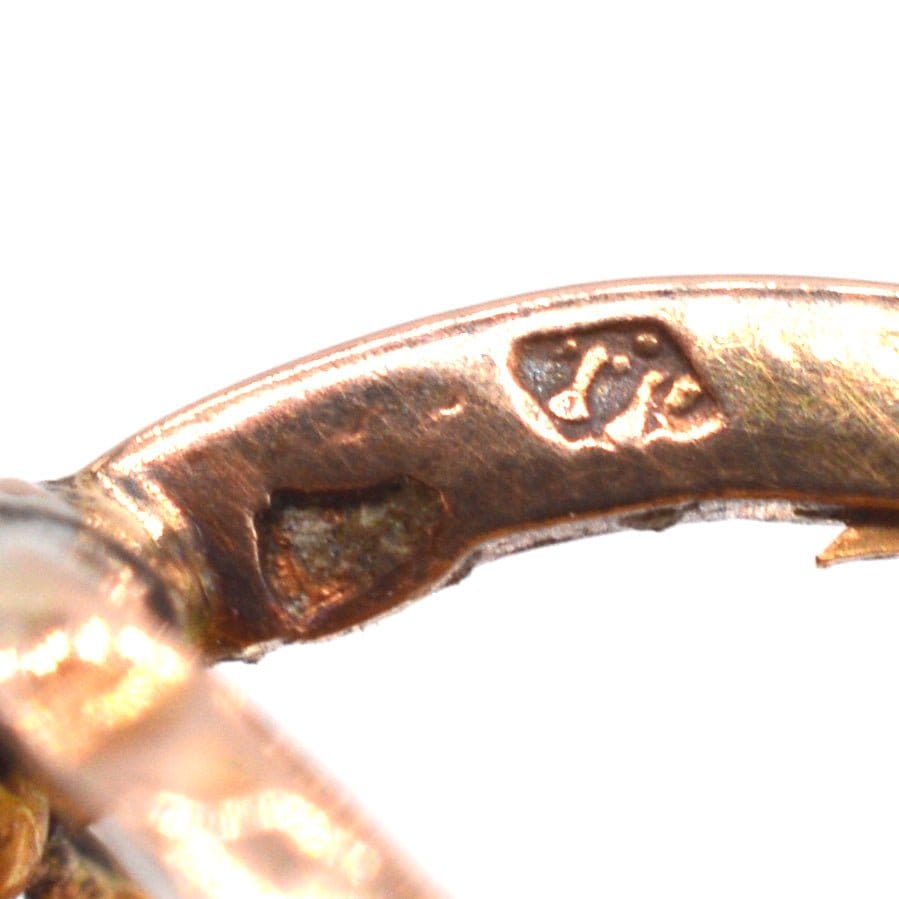 Close-up of 18ct gold stamp on French mini hoop earrings, featuring horse head symbol.
