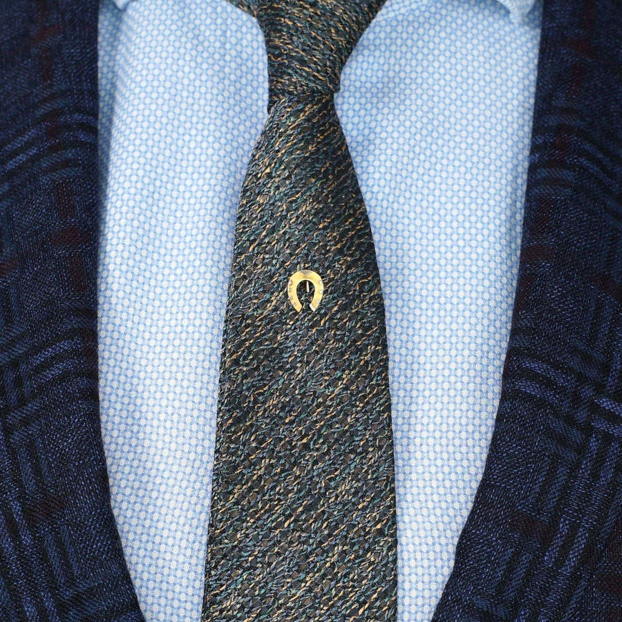 Late Victorian 15ct gold lucky horseshoe tie pin on a textured blue and gray tie.
