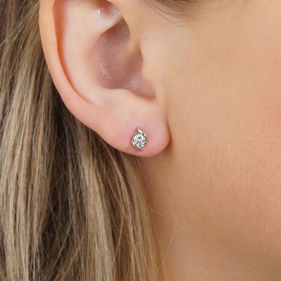 18ct white gold diamond stud earrings with twist detail worn on ear, showcasing brilliant sparkle and elegance.