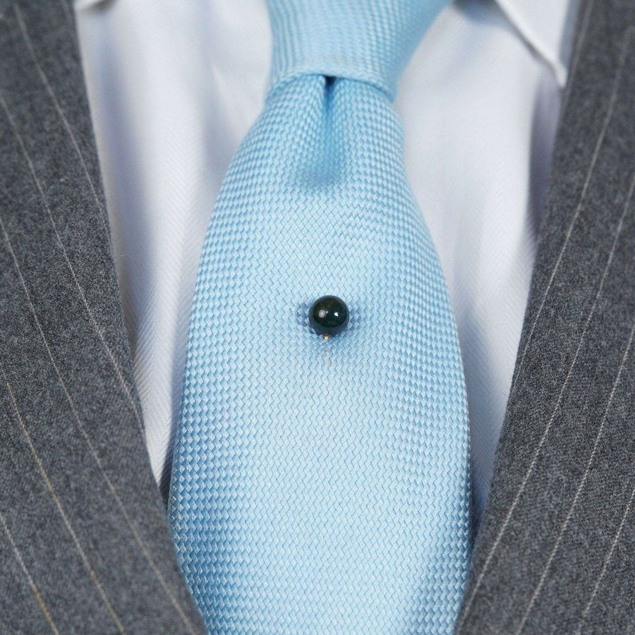 Victorian gold tie pin featuring a bloodstone sphere on a blue tie, showcasing elegance and sophistication.