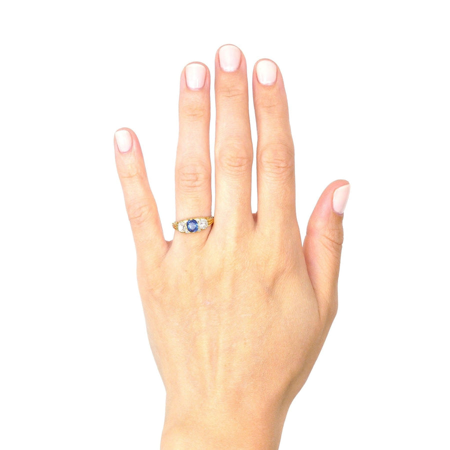 Victorian-style 18ct gold three stone sapphire and diamond ring displayed on a hand, showcasing its elegant design.