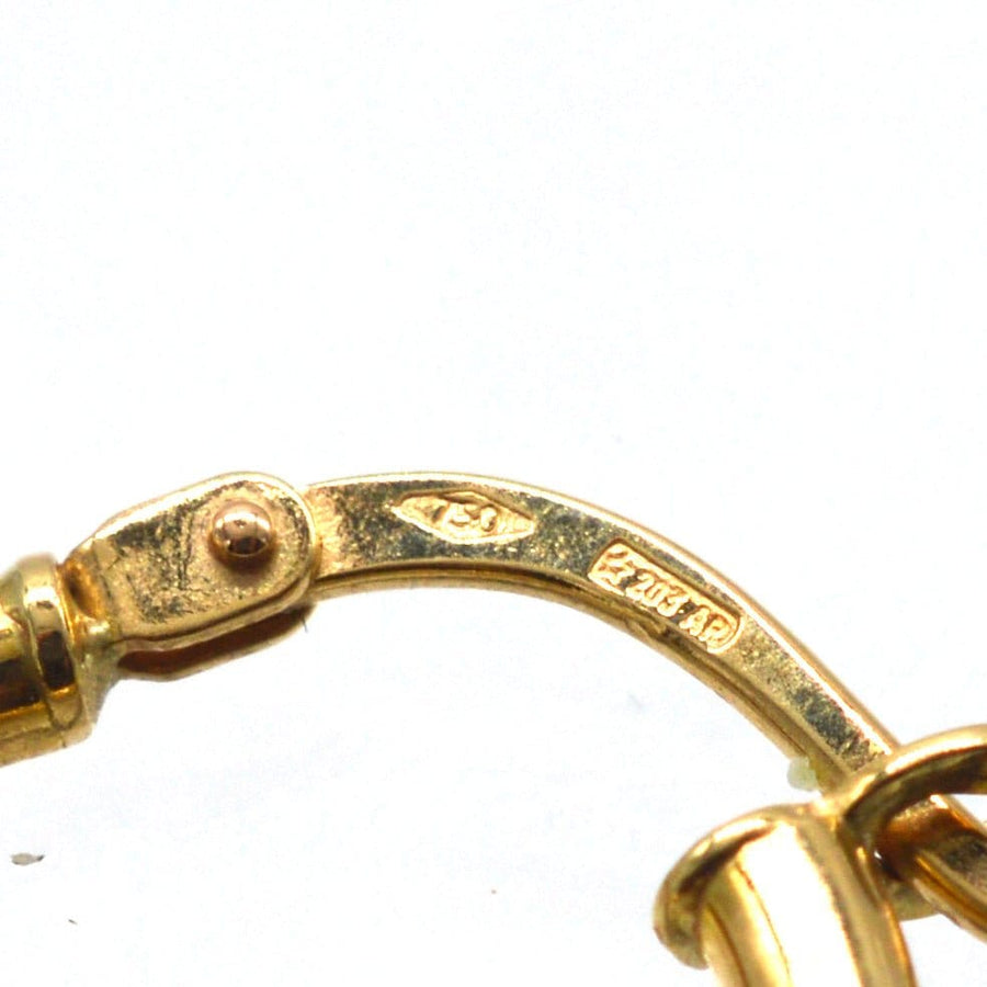 Close-up of vintage 18ct gold huggie earring clasp, showcasing intricate details and stamp.