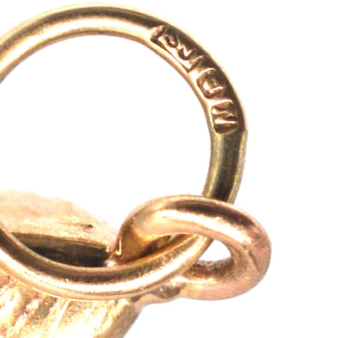 Close-up of a 9ct gold mussel shell charm showing the stamp and attachment loop.