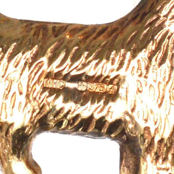Close-up of a vintage 9ct gold Scottie dog charm pendant, detailing stamp and texture.