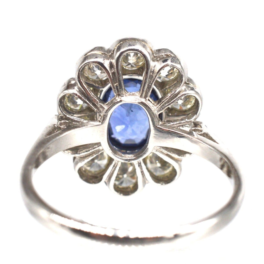 Vintage platinum sapphire and diamond cluster ring featuring a 1 carat sapphire surrounded by diamonds.