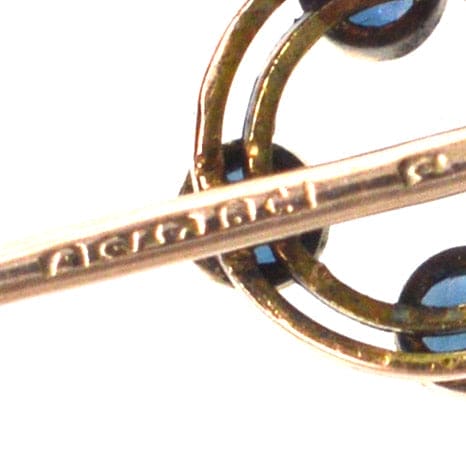 Close-up of an Art Deco 9ct gold circular tie pin featuring four sapphires, hallmarked Chester 1924.
