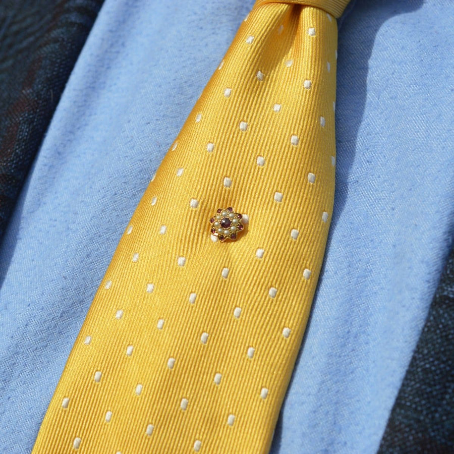 Edwardian gold garnet and pearl cluster tie pin on a yellow polka dot tie, enhancing elegant menswear style.