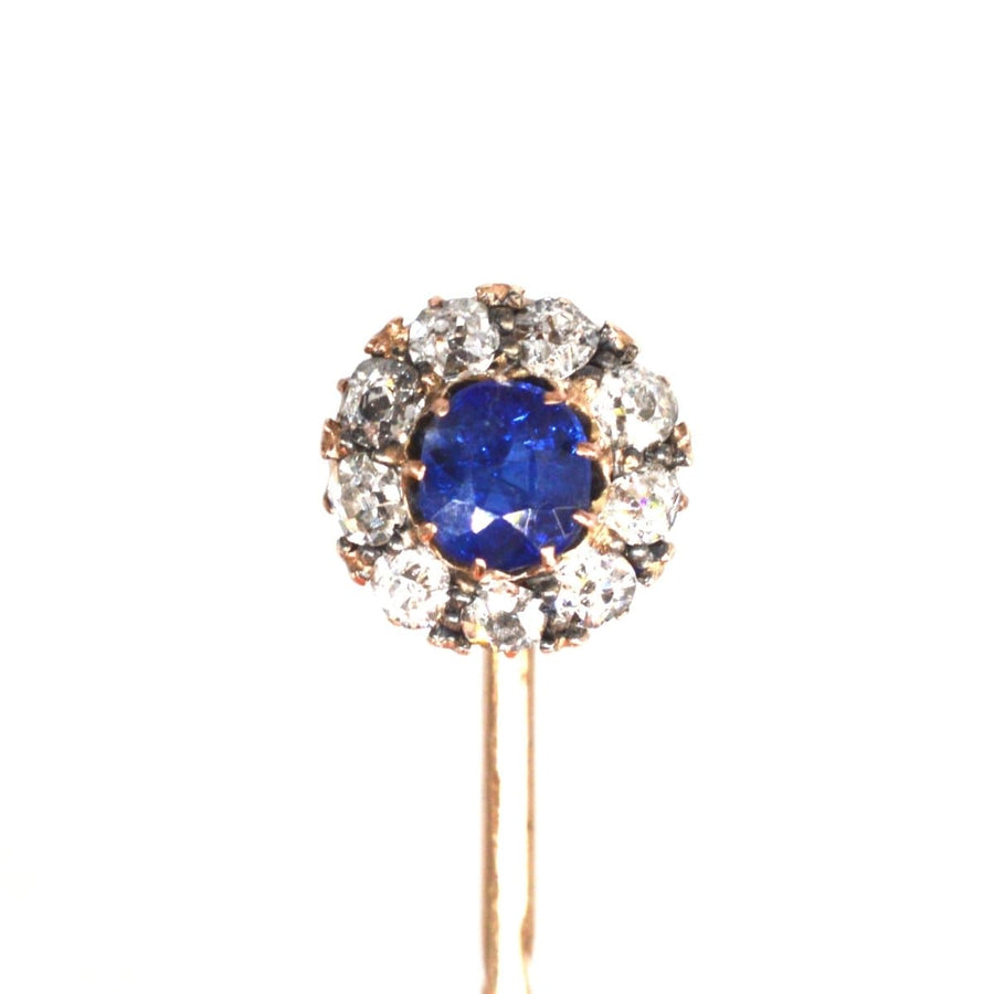 Edwardian rose gold tie pin featuring a blue sapphire surrounded by diamond clusters, circa 1900-1910s.