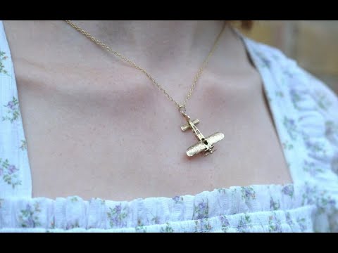 佩戴的是一条 20 世纪 70 年代的 9K 金复古 Aerolane 吊坠项链，带有旋转螺旋桨细节。