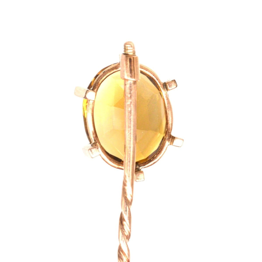 Close-up of a retro 1940s 9ct gold tie pin featuring a large golden citrine stone in a claw setting.