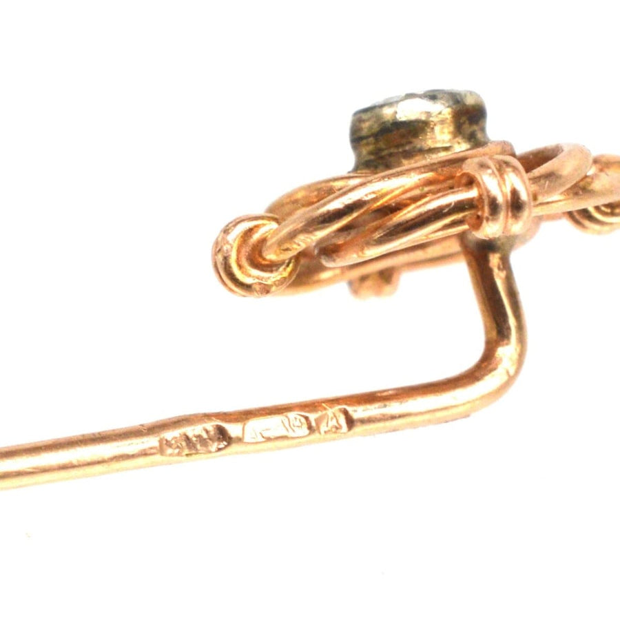 Close-up of a vintage Austro-Hungarian gold and diamond knot tie pin, showcasing intricate details and hallmark.