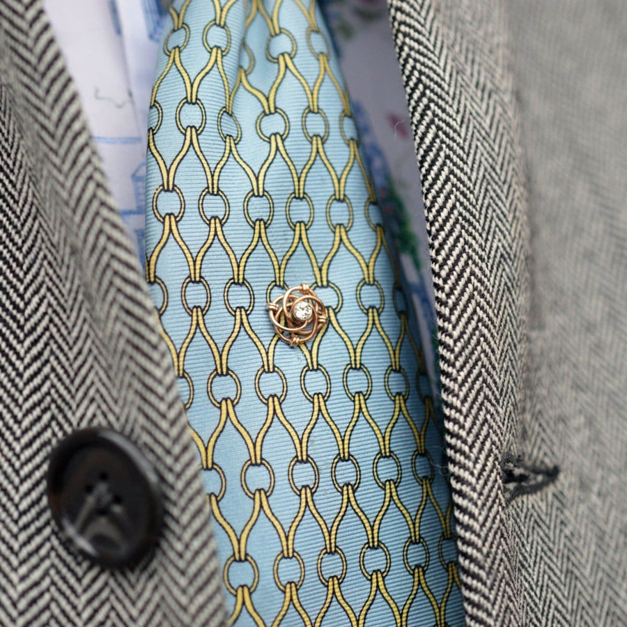 14ct gold and diamond knot tie pin on a colorful silk tie, featured on a stylish blazer.