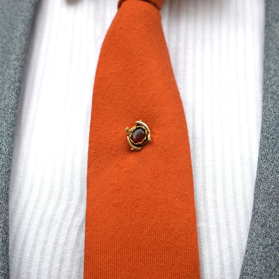 Edwardian 9ct gold tie pin with a red cabochon paste set on a vibrant orange tie.