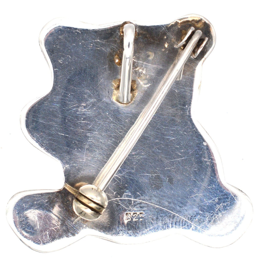 Vintage silver teddy bear brooch from the 1950s, featuring a bow tie and a loop for versatile wear.